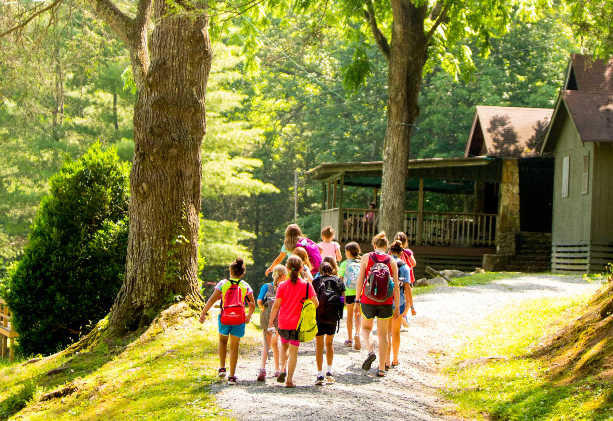 Group of Camp Highlander campers walking together up a wooded path toward their cabin in Mills River, North Carolina